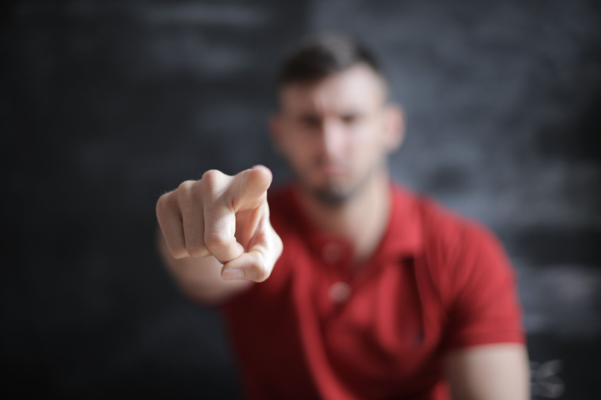 Man wijst met zijn vinger richting de camera; de vinger is scherp in beeld, zijn gezicht onscherp.